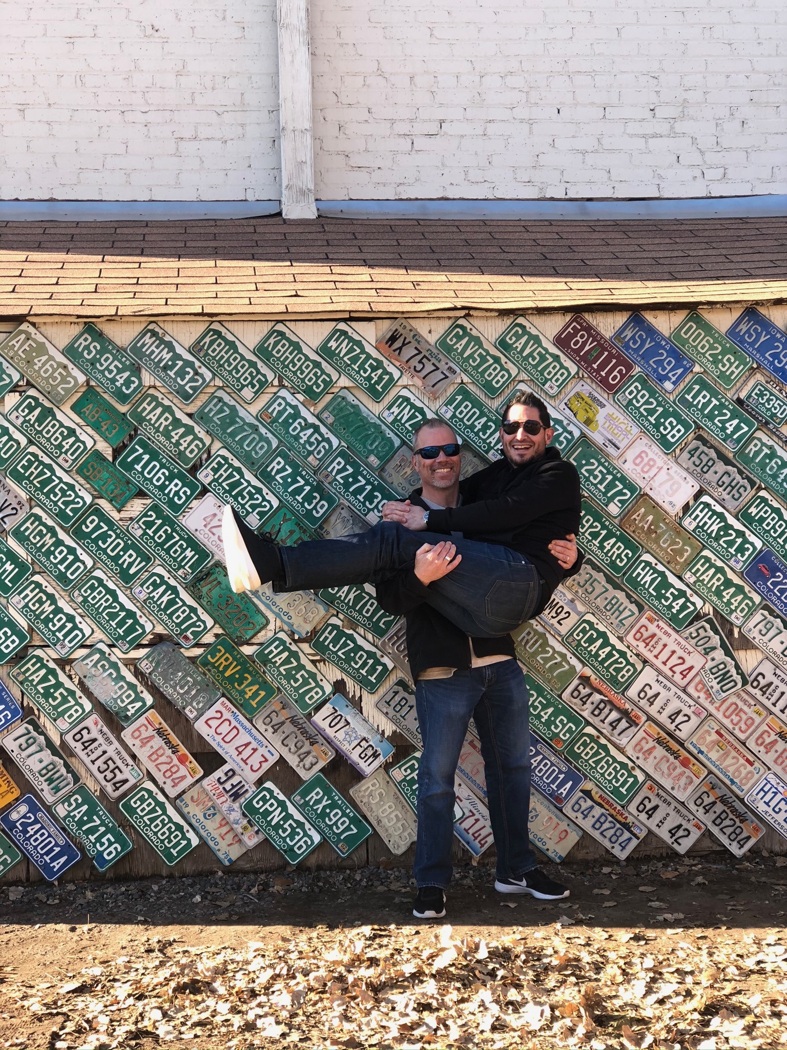 Mike ‘Bad’ Jadd holding Martin in front of a wall of license plates