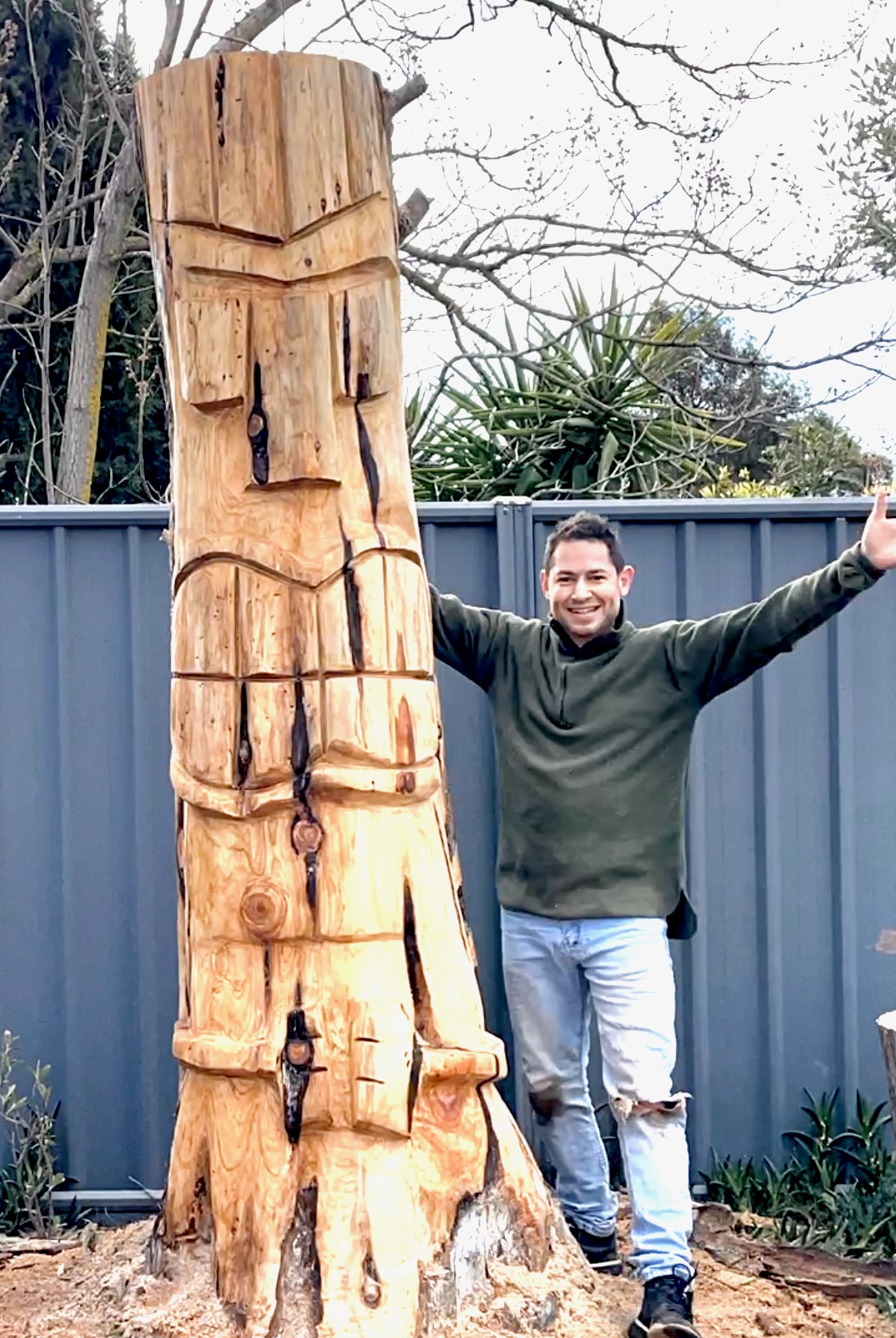 Martin standing beside his hand-carved Tane Mahuta